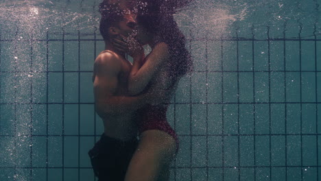 underwater-couple-kissing-in-swimming-pool-young-people-in-love-enjoying-romantic-kiss-passionate-lovers-submerged-in-water-floating-with-bubbles-in-playful-intimacy