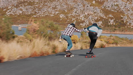 young-friends-longboarding-together-holding-hands-cruising-downhill-racing-happy-teenagers-enjoying-riding-skateboard-on-beautiful-countryside-road-rear-view
