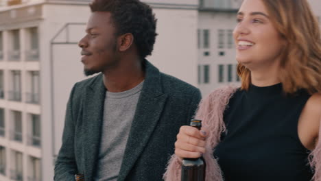 happy-multiracial-couple-laughing-having-fun-enjoying-rooftop-view-of-city-chatting-sharing-connection-friends-drinking-alcohol-hanging-out-on-weekend