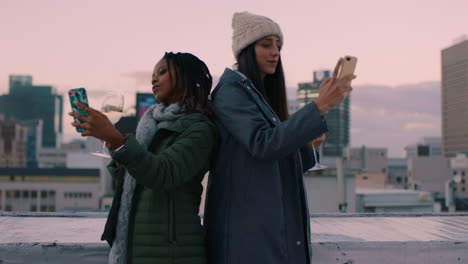 beautiful-young-women-friends-taking-selfies-using-smartphone-enjoying-mobile-camera-technology-hanging-out-on-rooftop-at-sunset-drinking-wine