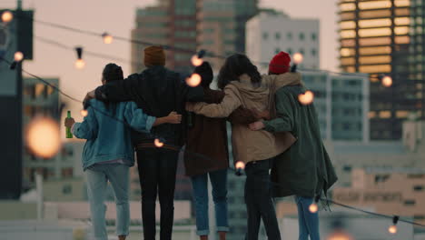 happy-group-of-friends-on-rooftop-with-arms-raised-celebrating-friendship-enjoying-hanging-out-together-drinking-alcohol-embracing-freedom-looking-at-urban-city-skyline-at-sunset