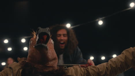 young-man-wearing-horse-mask-having-fun-sitting-in-shopping-cart-friends-enjoying-crazy-rooftop-party-at-night-playfully-celebrating-weekend