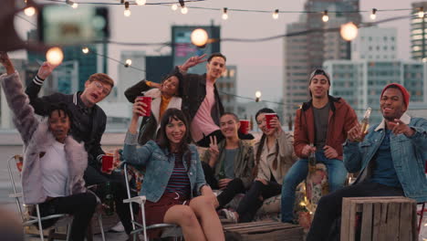multi-ethnic-group-of-friends-posing-for-photo-on-rooftop-party-at-sunset-students-enjoying-weekend-gathering-in-urban-city