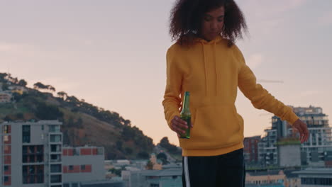 beautiful-young-african-american-woman-with-stylish-afro-walking-on-rooftop-edge-enjoying-weekend-lifestyle-drinking-alcohol-at-sunset