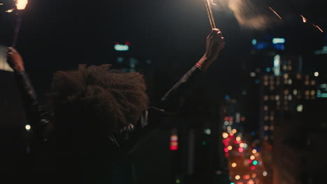 happy-young-african-american-woman-holding-sparklers-dancing-on-rooftop-at-night-celebrating-new-years-eve-enjoying-holiday-celebration