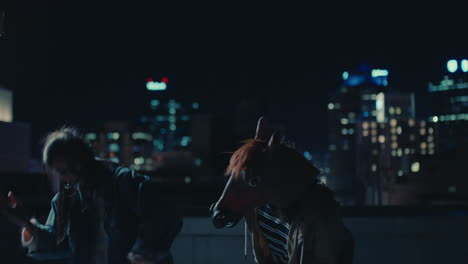 funny-man-wearing-horse-mask-dancing-with-friends-on-rooftop-having-fun-performing-silly-dance-moves-celebrating-weekend-together-in-urban-city-skyline