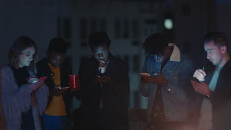 group-of-friends-relaxing-on-rooftop-at-night-using-smartphone-technology-texting-sharing-social-media-lifestyle-browsing-online-enjoying-weekend-party