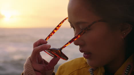 Porträt-Einer-Glücklichen-Asiatischen-Frau-Mit-Sonnenbrille,-Die-Den-Urlaub-Genießt-Und-Den-Reiselebensstil-Erkundet,-Sich-Am-Strand-Entspannt-Und-Sich-Bei-Sonnenuntergang-Positiv-Fühlt