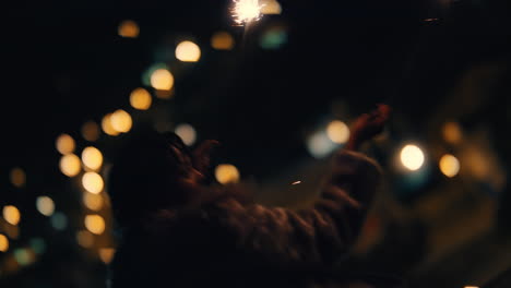happy-woman-holding-sparklers-on-rooftop-at-night-playfully-waving-arms-raised-celebrating-new-years-eve-enjoying-independence-day-celebration-with-city-lights-in-background