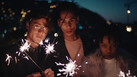 group-of-friends-holding-sparklers-celebrating-new-years-eve-on-rooftop-at-night-posing-with-beautiful-city-lights-in-background
