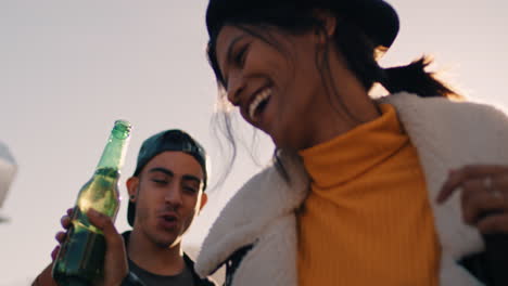 slow-motion-group-of-multiracial-friends-hanging-out-young-mixed-race-woman-dancing-enjoying-rooftop-party-at-sunset-drinking-alcohol-having-fun-on-weekend-celebration