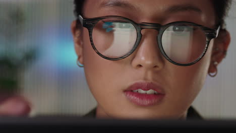 Nahaufnahme-Eines-Porträts-Einer-Schönen-Asiatischen-Geschäftsfrau,-Die-Bis-Spät-In-Die-Nacht-Arbeitet-Und-Einen-Tablet-Computer-Nutzt,-Indem-Sie-Finanzdiagrammdaten-Durchsucht-Und-Informationen-Auf-Dem-Bildschirm-Betrachtet-Und-Eine-Brille-Trägt