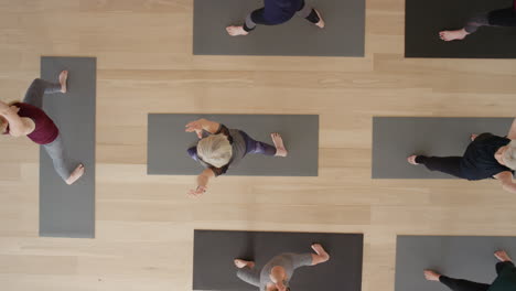 Yoga-Kurslehrerin-Von-Oben-Unterrichtet-Reife-Frauen-In-Kriegerpose-Und-Genießt-Einen-Gesunden-Lebensstil-Im-Fitnessstudio