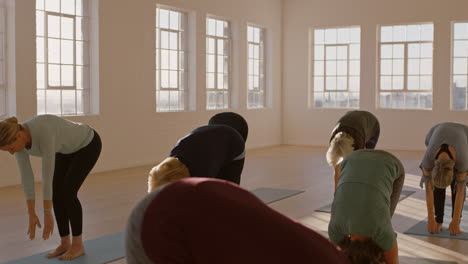 Yoga-Kurs-Mit-Gesunden,-Reifen-Frauen-übt-Die-Vorwärtsbeuge-Pose-Im-Stehen-Und-Genießt-Das-Morgendliche-Körperliche-Fitnesstraining-Im-Studio-Bei-Sonnenaufgang