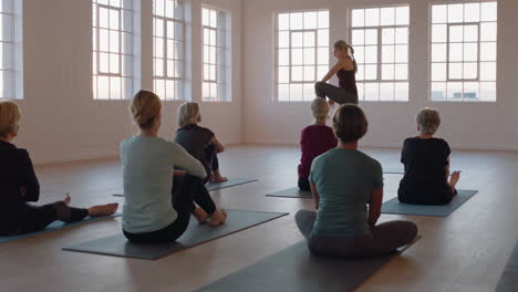 Instructor-De-Clase-De-Yoga-Enseñando-A-Un-Grupo-De-Mujeres-Maduras-Practicando-Meditación-Mostrando-Pose-Disfrutando-Del-Ejercicio-Físico-Matutino-En-El-Estudio