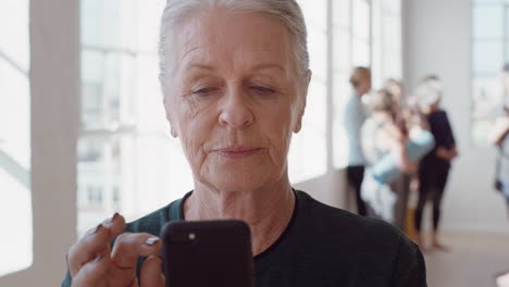 Retrato-De-Cerca-De-Una-Hermosa-Anciana-Usando-Un-Teléfono-Inteligente-En-Una-Clase-De-Yoga-Compartiendo-Un-Estilo-De-Vida-Saludable-En-Las-Redes-Sociales-Disfrutando-De-Prácticas-De-Meditación-En-Línea-En-Un-Gimnasio
