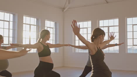 Yoga-Kurslehrer-Unterrichtet-Schwangere-Frauen,-Die-Einen-Gesunden-Lebensstil-Ausüben,-üben-Krieger-Pose-Und-Genießen-Das-Körperliche-Fitnesstraining-In-Der-Gruppe-Im-Studio-Bei-Sonnenaufgang