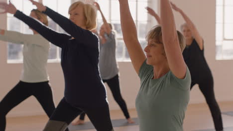 Yoga-Kurs-Gesunde-Reife-Frau-Praktiziert-Kriegerpose-Und-Genießt-Gruppentraining-Im-Fitnessstudio