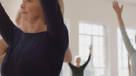 Yoga-Kurs-Mit-Gesunden,-Reifen-Frauen,-Die-Kriegerpose-Praktizieren-Und-Körperliche-Fitness-Genießen,-Trainingslehrer-Unterrichtsgruppe-Im-Übungsstudio