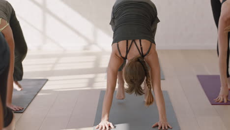 young-pregnant-caucasian-woman-in-yoga-class-practicing-downward-facing-dog-pose-enjoying-healthy-lifestyle-group-exercising-in-fitness-studio