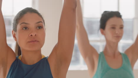 Yoga-Kurs,-Gesunde-Frau-Mit-Gemischter-Abstammung,-Die-Kriegerpose-Praktiziert-Und-Den-Fitness-Lebensstil-Genießt-Und-Mit-Multiethnischen-Menschen-Im-Trainingsstudio-Trainiert