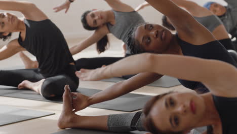 Mujer-De-Yoga-Saludable-Practicando-Pose-De-Curva-Lateral-Sentada-Joven-Afroamericana-Disfrutando-De-Un-Estilo-De-Vida-Físico-Haciendo-Ejercicio-En-Estudio-Con-Un-Grupo-De-Mujeres-Multirraciales