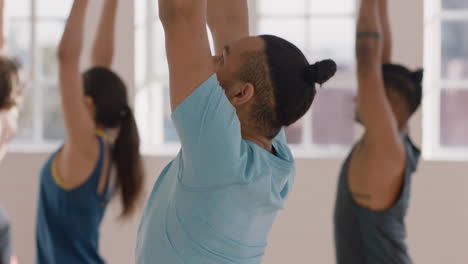 Yoga-Kurs,-Gesunder-Hispanischer-Mann,-Der-Kriegerpose-Praktiziert-Und-Den-Fitness-Lebensstil-Genießt,-Indem-Er-Mit-Gemischtrassigen-Menschen-Im-Trainingsstudio-Trainiert