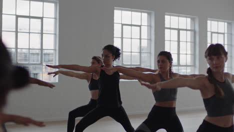yoga-class-group-of-multiracial-women-practicing-warrior-pose-enjoying-healthy-lifestyle-exercising-in-fitness-studio-instructor-teaching-group-meditation-at-sunrise
