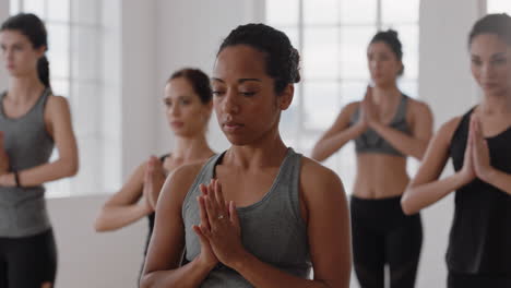 Mujer-De-Yoga-De-Raza-Mixta-Saludable-Practicando-Meditación-En-Pose-De-Oración-Con-Un-Grupo-De-Mujeres-Multirraciales-Disfrutando-De-Un-Estilo-De-Vida-Físico-Ejercitando-Un-Cuerpo-Flexible-En-Un-Estudio-De-Entrenamiento