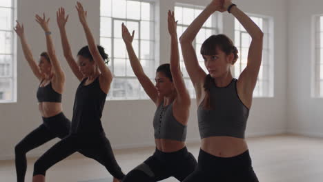 yoga-class-group-of-multiracial-women-practicing-warrior-pose-enjoying-healthy-lifestyle-exercising-in-fitness-studio-at-sunrise