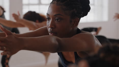 Schöne-Afroamerikanische-Yoga-Frau-Praktiziert-Krieger-Pose-Meditation-Mit-Einer-Gruppe-Gemischtrassiger-Frauen,-Die-Einen-Gesunden-Lebensstil-Genießen-Und-Im-Fitnessstudio-Trainieren