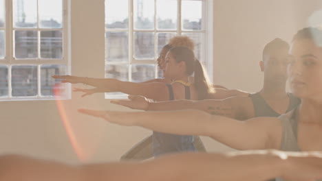 yoga-class-of-young-healthy-people-practicing-warrior-pose-instructor-woman-teaching-diverse-group-enjoying-fitness-lifestyle-exercising-in-studio-at-sunrise