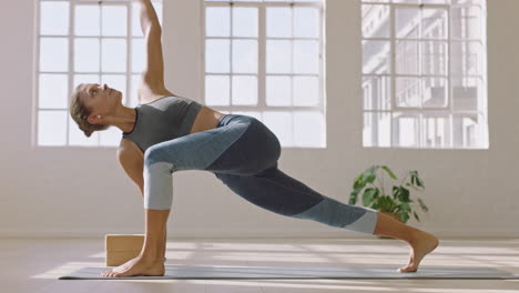 Gesunde-Yoga-Frau-Praktiziert-Eine-Pose-Im-Erweiterten-Seitenwinkel-Und-Genießt-Den-Fitness-Lebensstil,-Indem-Sie-Im-Studio-Trainiert-Und-Bei-Sonnenaufgang-Ein-Schönes-Körpertraining-Auf-Einer-Trainingsmatte-Ausdehnt