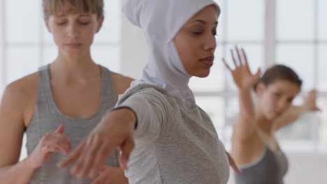 Yoga-Klasse,-Schöne-Muslimische-Frau,-Die-Kriegerpose-Praktiziert,-Fitnesstrainerin,-Die-Eine-Gruppe-Multiethnischer-Frauen-Unterrichtet,-Gesunde-Meditationspraxis-Im-Trainingsstudio