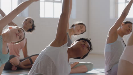 Yoga-Kurs:-Gesunde-Frau-Mit-Gemischter-Abstammung-übt-Sitzende-Seitenbeuge-Pose-Mit-Einer-Gruppe-Schöner-Frauen,-Die-Auf-Einer-Trainingsmatte-Sitzen-Und-Bei-Sonnenaufgang-Ein-Training-Für-Einen-Gesunden-Lebensstil-Im-Fitnessstudio-Genießen