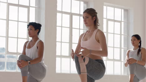 Yoga-Kurslehrer-Unterrichtet-Krieger-Pose-Für-Eine-Schöne-Gruppe-Von-Frauen,-Die-Einen-Gesunden-Lebensstil-Genießen-Und-In-Der-Fitness-Studio-Meditation-Trainieren