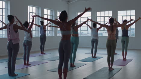 yoga-class-of-healthy-women-practicing-standing-forward-bend-pose-enjoying-exercising-in-fitness-studio-instructor-leading-group-meditation-teaching-workout-posture-at-sunrise