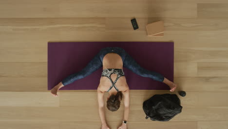 overhead-view-flexible-yoga-woman-practicing-wide-angle-seated-forward-bend-pose-enjoying-healthy-lifestyle-exercising-in-fitness-studio-training-on-exercise-mat