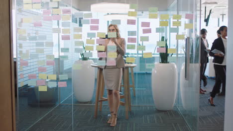 beautiful-business-woman-using-smartphone-taking-photo-of-sticky-notes-proud-of-successful-problem-solving-strategy-ideas-with-creative-mind-map-working-in-office-4k