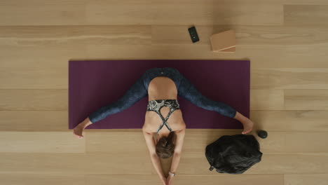 overhead-view-flexible-yoga-woman-practicing-wide-angle-seated-forward-bend-pose-enjoying-healthy-lifestyle-exercising-in-fitness-studio-training-on-exercise-mat