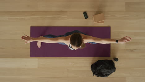 Ansicht-Von-Oben:-Flexible-Yoga-Frau,-Die-Kriegerpose-Praktiziert-Und-Einen-Gesunden-Lebensstil-Genießt,-Indem-Sie-Im-Fitnessstudio-Auf-Einer-Trainingsmatte-Trainiert