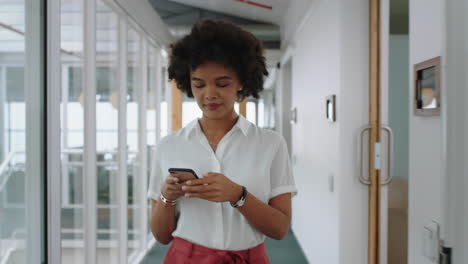 mixed-race-business-woman-using-smartphone-walking-through-office-texting-sending-emails-successful-female-executive-checking-messages-on-mobile-phone-arriving-at-workplace-4k