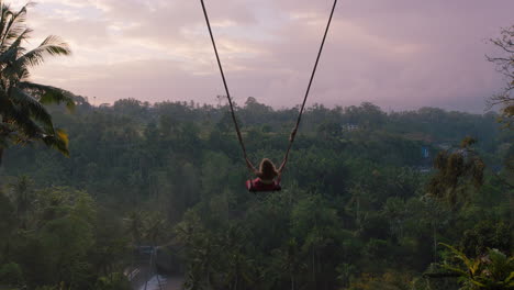 tourist-woman-swinging-over-tropical-jungle-at-sunrise-travel-girl-enjoying-exotic-vacation-sitting-on-swing-in-having-fun-holiday-lifestyle-freedom-4k