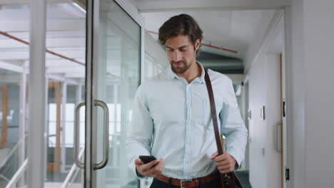 attractive-businessman-using-smartphone-walking-through-office-texting-sending-emails-successful-male-executive-checking-messages-on-mobile-phone-arriving-at-workplace-4k