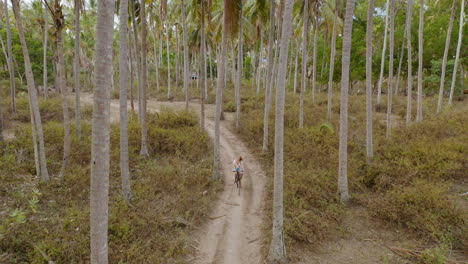 Luftaufnahme,-Frau,-Die-Fahrrad-Fährt-Und-Die-Tropische-Insel-Erkundet.-Mädchen,-Das-Auf-Reisen-Ist-Und-Den-Wunderschönen-Palmenwald-4k-Genießt