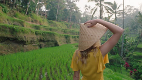 Mujer-De-Viaje-En-Arrozal-Con-Vestido-Amarillo-Con-Sombrero-Explorando-Una-Exuberante-Terraza-De-Arroz-Verde-Caminando-En-Un-Paisaje-Cultural-Vacaciones-Exóticas-A-Través-De-Bali-Indonesia-Descubrir-Asia