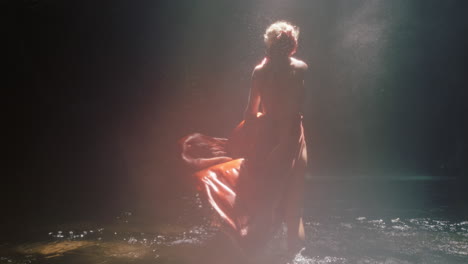 Schöne-Frau,-Die-In-Einer-Wasserfallhöhle-Tanzt-Und-Ein-Wunderschönes-Kleid-Trägt,-Genießt-Das-Tanzgefühl-Spiritueller-Freiheit-4K
