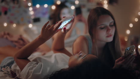 happy-teenage-girls-lying-on-bed-using-smartphones-browsing-social-media-texting-sharing-gossip-enjoying-sleep-over-on-weekend