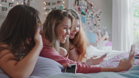 happy-teenage-girls-taking-selfie-photos-using-smartphone-best-friends-hanging-out-at-home-lying-on-bed-enjoying-weekend-together