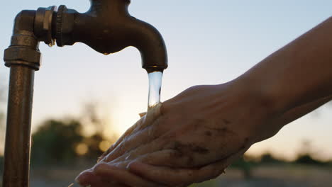 close-up-woman-washing-hands-under-tap-with-fresh-water-on-rural-farmland-at-sunrise